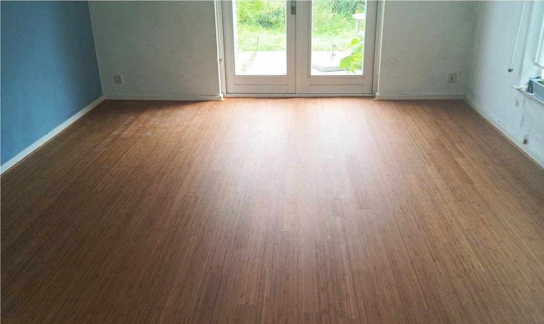 Woonkamer met een afgewerkte bamboevloer met vloerverwarming eronder, en openslaande deuren naar de tuin
